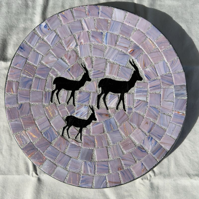 Round mosaic wall plate with three springbok silhouettes on a soft lavender background