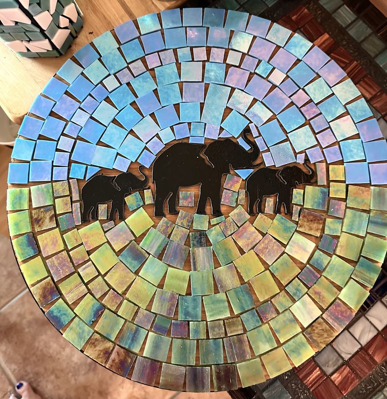 Round mosaic bowl with three elephants beneath an acacia tree on iridescent blue-and-gold glass