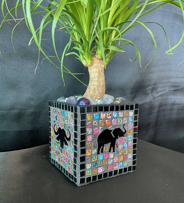 Square mosaic planter with black elephants on a multicolor pixel mosaic pattern, planted with a ponytail palm