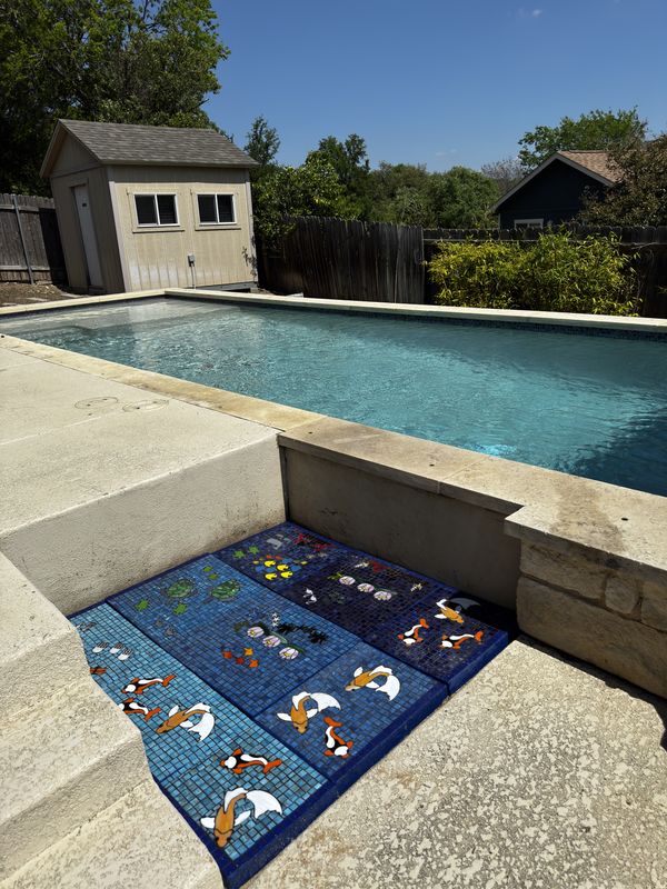 Custom mosaic panels in a space beside a pool, featuring koi, turtles, and tropical fish in blue glass tile