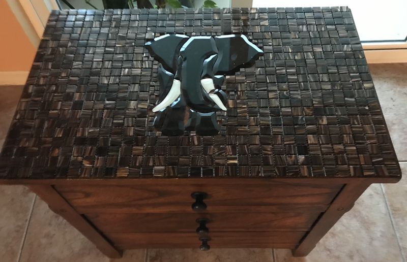 Rectangular wooden side table with mosaic top depicting a three-dimensional elephant head in bronze and dark brown glass