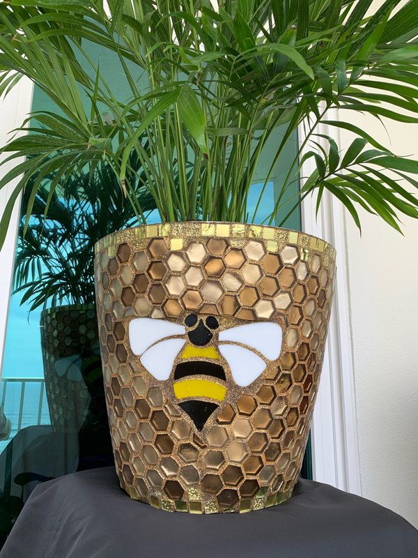 Tall tapered planter in gold hexagonal mosaic with a bumblebee motif, planted with parlor palm